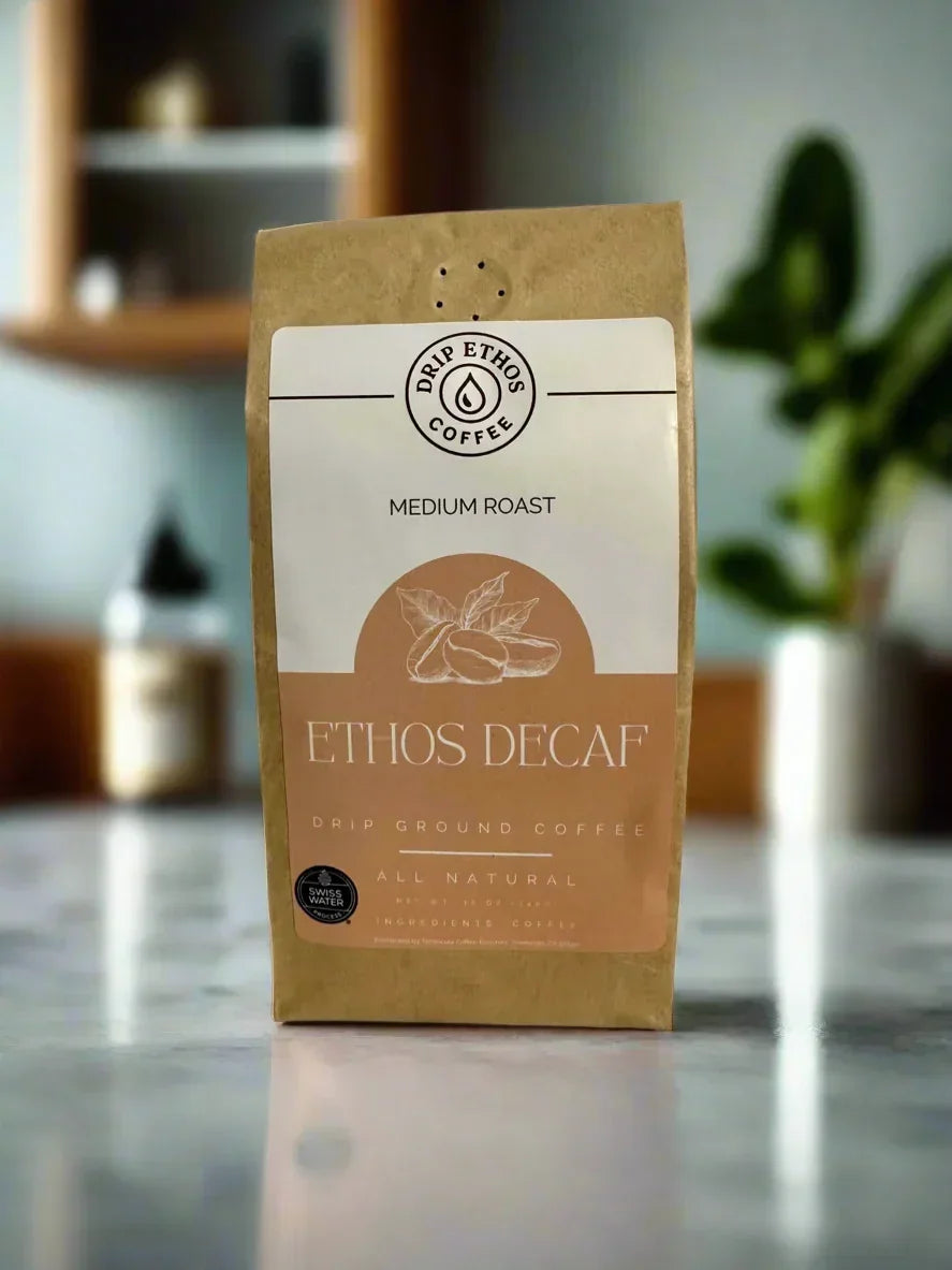 Ethos Decaf medium roast drip ground coffee bag on a marble countertop with blurred plant in background